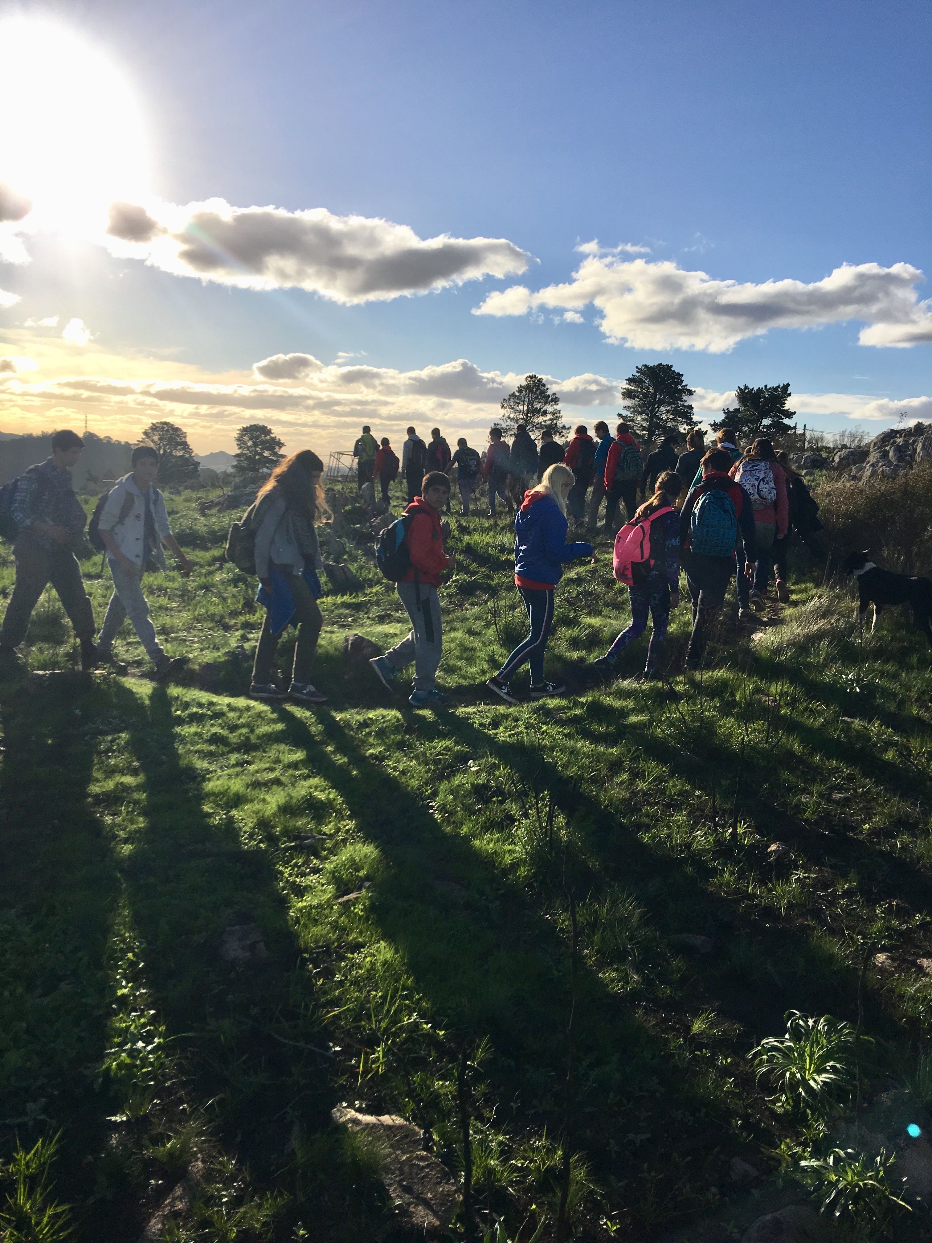 niños y niñas caminando por las sierras una tarde soleada